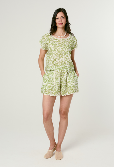 Woman wearing a green floral short set on a white background