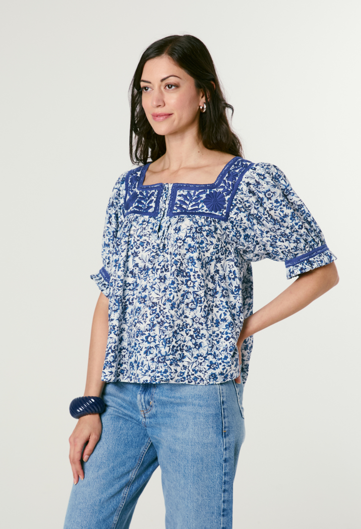 Woman wearing a blue floral blouse and jeans on a white background