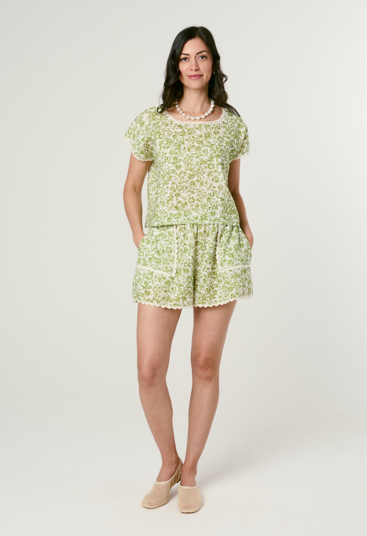 Woman wearing a green floral short set on a white background