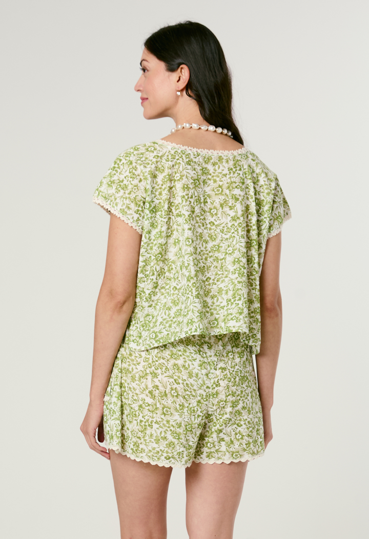 Woman wearing a green floral short set on a white background
