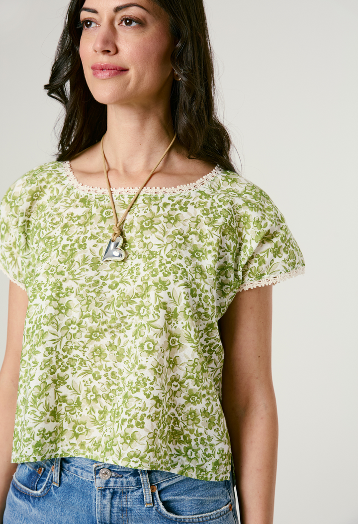 Model wearing green floral blouse and jeans