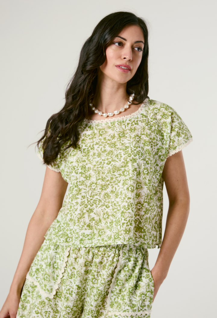 Woman wearing a green floral short set against a plain background