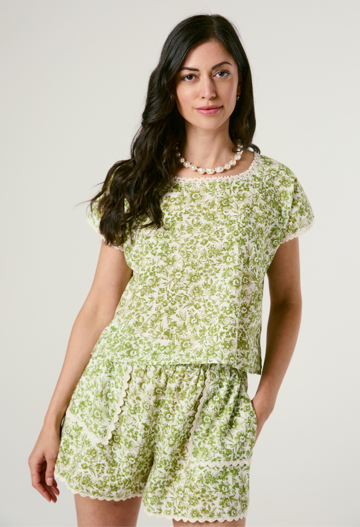 Woman wearing a green floral short set on a plain background